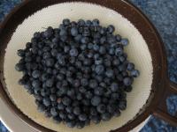 Sort blueberries and wash them in a strainer under...